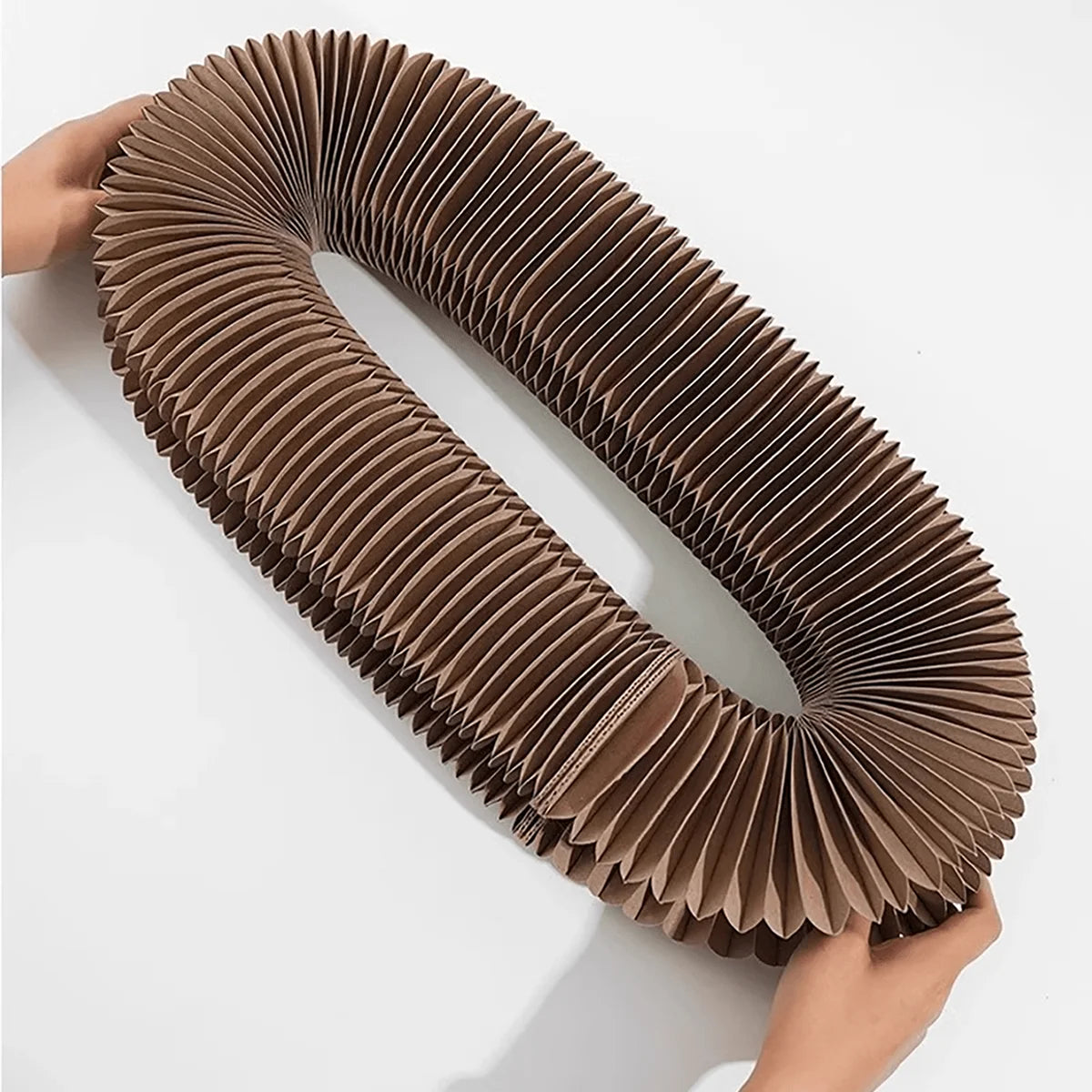 Cat scratcher stretched open between two hands, showing the folded cardboard