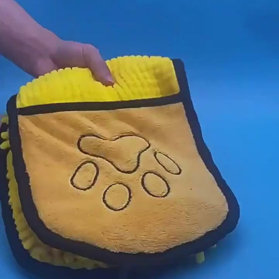 Hands slipping into the towel's pockets to dry a dog